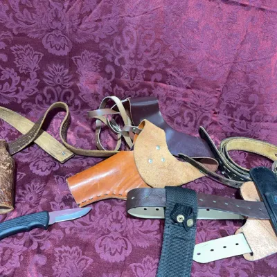 Sale Photo Thumbnail #58: Assortment of leather gun holsters, gun belts, nylon tactical accessories, and a small fixed-blade utility knife.