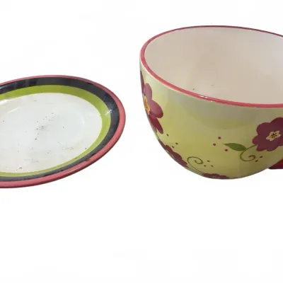 Sale Photo Thumbnail #258: Oversized yellow ceramic teacup and saucer set featuring painted purple flowers and a colorful striped rim.