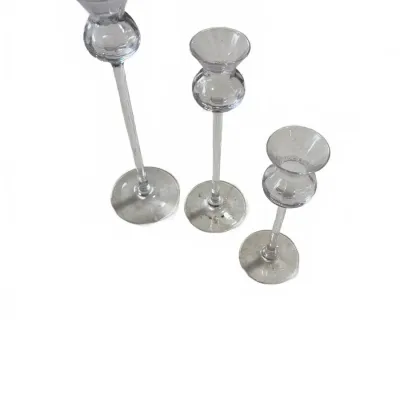 Sale Photo Thumbnail #284: Set of three graduated hand-blown clear glass candlestick holders with slender stems and bulbous tops.
