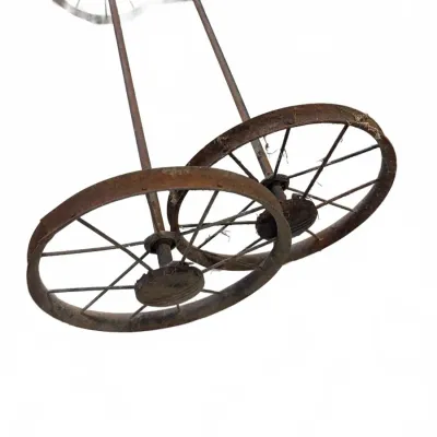 Sale Photo Thumbnail #263: Vintage rusted iron carriage or cart wheel assembly with thin spokes, showing heavy surface patina and wear.