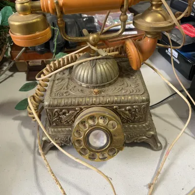Sale Photo Thumbnail #161: Vintage ornate brass-tone rotary telephone with a French style handset and amber plastic accents.