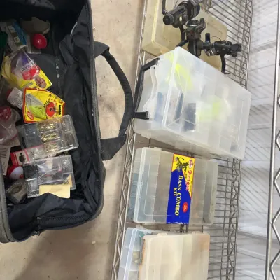 Sale Photo Thumbnail #29: Collection of fishing gear including a soft-sided tackle bag, plastic organizer boxes filled with lures and accessories, and fishing reels.