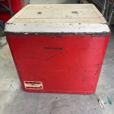 Sale Photo Thumbnail #167: Vintage red and white Cold-Flyte metal cooler with swinging wire handle, showing age-appropriate rust, scratches, and paint wear.