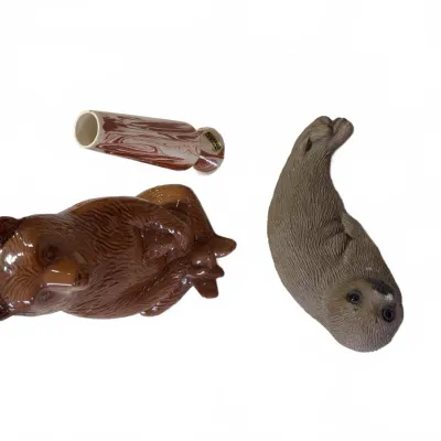 Sale Photo Thumbnail #274: Collection of three decorative items including a glazed brown bear figurine, a detailed seal figurine, and a small marbled ceramic bud vase.