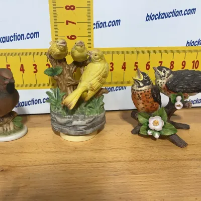Sale Photo Thumbnail #142: Collection of three hand-painted porcelain bird figurines, featuring songbirds and robins perched on branches.
