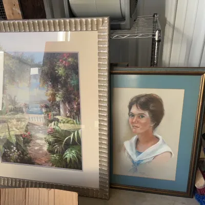 Sale Photo Thumbnail #15: Two framed artwork pieces, including a large garden landscape print in a fluted champagne frame and a pastel portrait of a young woman in a blue mat with a gold frame.