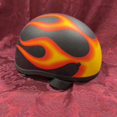 Sale Photo Thumbnail #7: Matte black half-shell motorcycle helmet featuring a vibrant red and yellow flame graphic and adjustable chin strap.