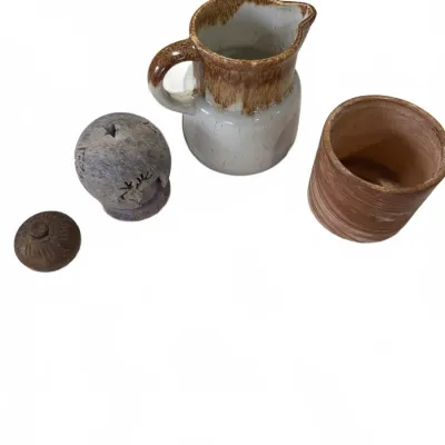 Sale Photo Thumbnail #275: Collection of small decorative pottery items including a brown and white drip-glazed pitcher, a carved stone incense burner orb, and a terracotta tumbler.
