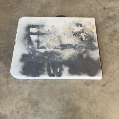 Sale Photo Thumbnail #80: Folded white plastic utility table with heavy black spray paint marks and surface wear.