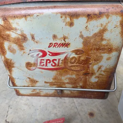 Sale Photo Thumbnail #249: Vintage mid-century metal Pepsi-Cola picnic cooler by Progress Refrigerator Co., showing significant surface rust, patina, and wear.