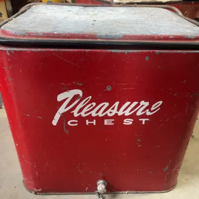 Sale Photo Thumbnail #166: Vintage red metal Pleasure Chest cooler with galvanized lid and drain spigot, showing minor paint wear and distressing.