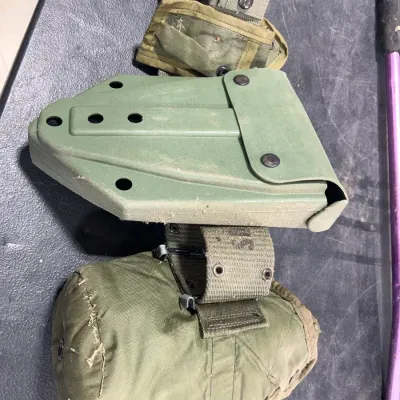 Sale Photo Thumbnail #52: Vintage military surplus olive drab web belt equipped with a plastic folding shovel carrier, canvas pouch, and canteen cover.