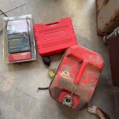 Sale Photo Thumbnail #241: Collection of garage items including a red plastic Blitz gas can, an HTOMT tool set in a hard case, a Whistler power inverter in original packaging, and a Prestone fluid tester.