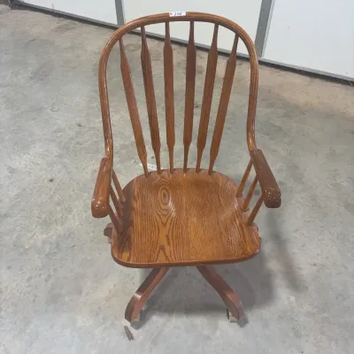 Sale Photo Thumbnail #61: Vintage golden oak swivel desk armchair featuring a spindle back, contoured wooden seat, armrests, and a four-star wheeled base.