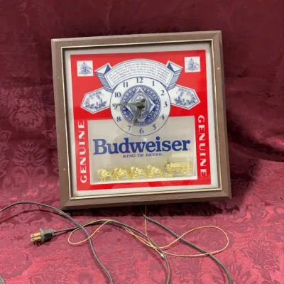 Sale Photo Thumbnail #17: Vintage electric Budweiser wall clock featuring a faux wood frame and a miniature gold-tone Clydesdale team and wagon scene.