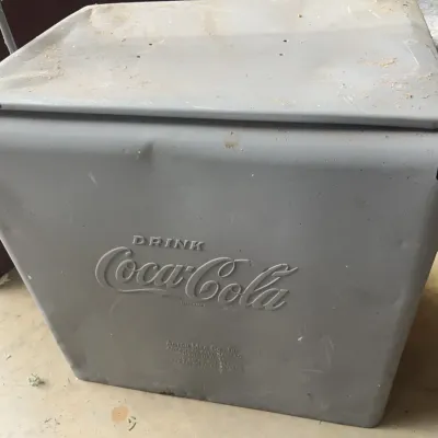 Sale Photo Thumbnail #164: Vintage repainted metal Coca-Cola cooler by Action Mfg. Co., featuring embossed lettering and metal handles, showing light surface wear and minor denting.