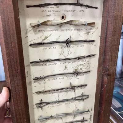 Sale Photo Thumbnail #25: Framed vintage barbed wire sample collection featuring labeled historical specimens dating from the 1870s and 1880s.