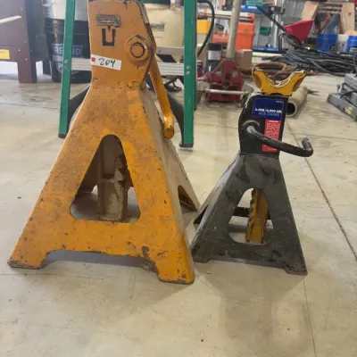 Sale Photo Thumbnail #65: Two heavy-duty automotive jack stands, including a large yellow stand and a 3-ton black stand.