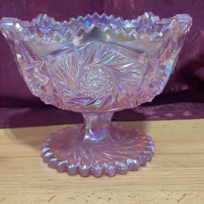 Sale Photo Thumbnail #129: Pink carnival glass pedestal compote bowl featuring a pinwheel pattern and serrated rim.
