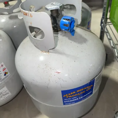 Sale Photo Thumbnail #180: Ozark Mountain Propane Co. 15 lb propane tank featuring a protective blue valve cap and light surface scuffing.