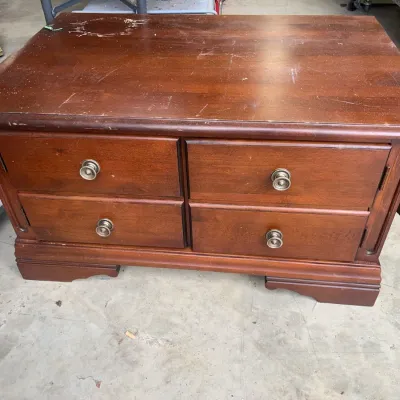 Sale Photo Thumbnail #163: Vintage drop-leaf wooden coffee table with four drawers and brass ring pulls, showing surface wear and scuffs on the top.