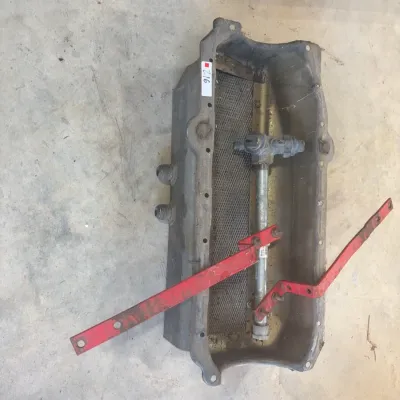 Sale Photo Thumbnail #77: Vintage cast aluminum engine oil pan with internal pickup tube assembly and red mounting brackets, showing light wear and grease residue.