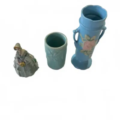 Sale Photo Thumbnail #285: Trio of vintage decorative ceramics including a southern belle porcelain figurine, a matte green pottery vase, and a blue Hull art pottery vase featuring a pink floral motif.