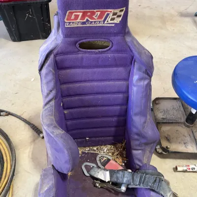 Sale Photo Thumbnail #42: Purple GRT Race Cars racing bucket seat with padded cover and safety harness, showing wear and debris from garage storage.