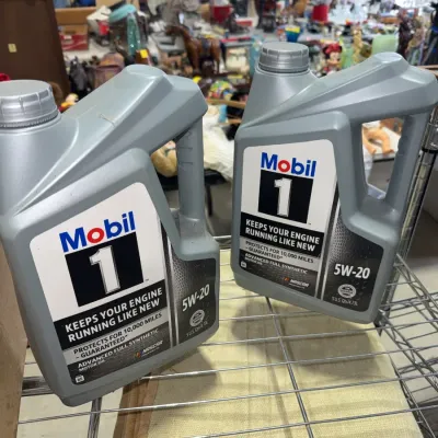 Sale Photo Thumbnail #208: Two 5-quart containers of Mobil 1 Advanced Full Synthetic 5W-20 motor oil sitting on a wire rack.