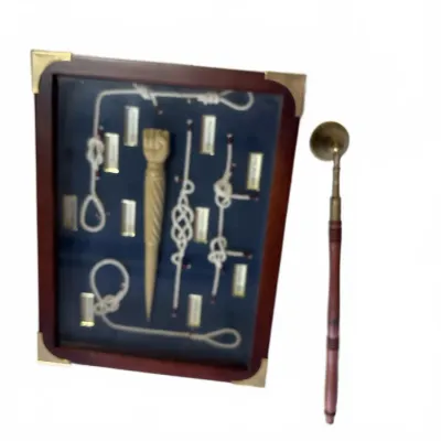 Sale Photo Thumbnail #282: Framed maritime knot display in a dark wood case with brass corners, accompanied by a wooden-handled brass boatswain's whistle or bell call instrument.