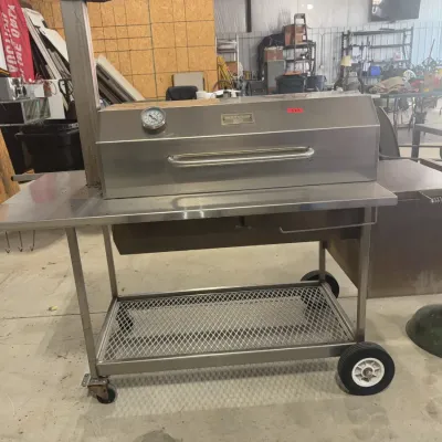Sale Photo Thumbnail #84: Large stainless steel BBQ Pits by Klose smoker grill on a wheeled cart, featuring an integrated thermometer and side firebox.