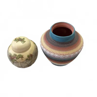 Sale Photo Thumbnail #266: Two decorative ceramic vessels, including a small ivory-colored ginger jar with elephant and leaf motifs alongside a Southwest-style pot featuring geometric etched patterns.