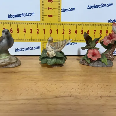Sale Photo Thumbnail #141: Set of three vintage painted porcelain bird figurines, featuring a sparrow, a dove on leaves, and a hummingbird with pink flowers.