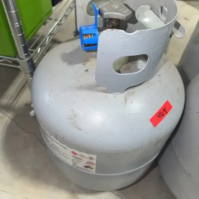 Sale Photo Thumbnail #181: Standard grey 20 lb propane tank with a protective safety cap on the valve, showing light wear.
