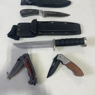 Sale Photo Thumbnail #148: Collection of tactical and hunting knives, including fixed-blade knives with matching sheaths and folding pocket knives.