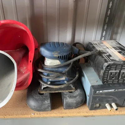 Sale Photo Thumbnail #19: Collection of workshop equipment including plastic funnels, a blue power hand sander, a BK Precision 1680 DC power supply, and a power inverter, showing light wear and dust.