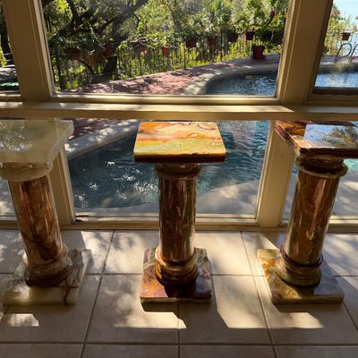 Set of three vintage polished onyx pedestals featuring classical column designs and square tops with natural stone veining.