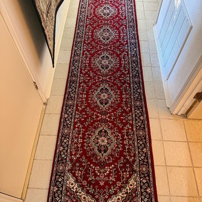 Traditional Persian-style runner rug with a deep red field and ornate central medallions, featuring fringe on the ends.