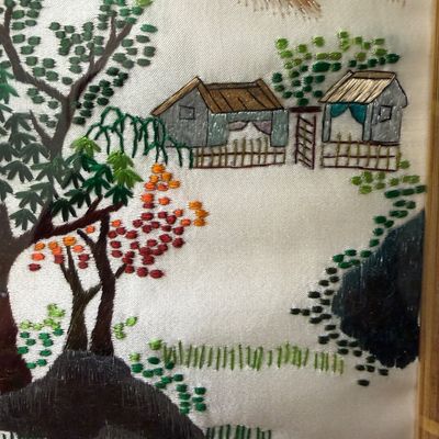 Framed silk embroidery artwork featuring a detailed Asian landscape with trees, houses, and mountains.