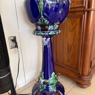 Art Nouveau style cobalt blue glazed majolica ceramic jardiniere with matching pedestal stand, featuring raised floral motifs.