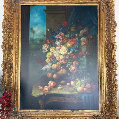 Large classical-style floral and fruit still life oil painting housed in an ornate, heavily carved giltwood frame.