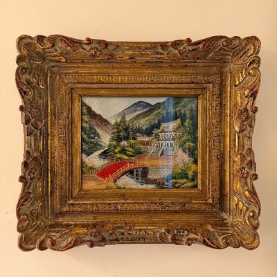 Japanese silk embroidery artwork depicting a pagoda, red bridge, and mountain landscape, presented in an ornate giltwood frame.