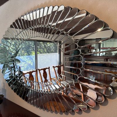 Large mid-century modern oval sunburst mirror featuring a segmented bevel-cut glass frame.