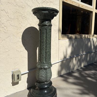 Carved green marble pedestal column with fluted column design and classical leaf motif details.