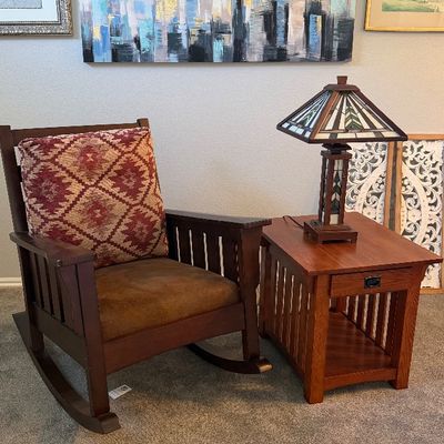 Mission Arts and Crafts style wooden rocking chair and matching side table topped with a stained glass Tiffany-style table lamp. A large...