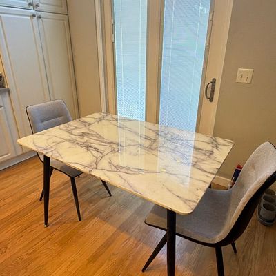 Modern dining set featuring a faux-marble rectangular tabletop with black tapered legs, paired with two light grey upholstered chairs.