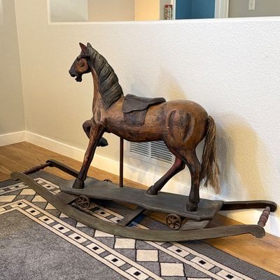 Vintage carved wooden rocking horse with a natural finish, leather saddle details, and real hair tail set on a dual-runner glider frame.