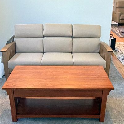 Mission-style wooden coffee table in a medium stain paired with a slatted-arm sofa upholstered in beige fabric.