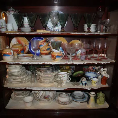 Sale Photo Thumbnail #127: Vintage display cabinet filled with glassware, china, tea sets, and decorative collectibles arranged across four shelves.