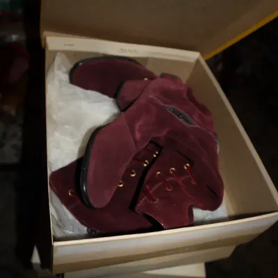Sale Photo Thumbnail #45: Pair of burgundy suede lace-up boots with brass eyelets inside their original shoebox.
